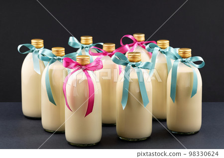 Homemade eggnog in bottles with blue and pink bows on dark background 98330624