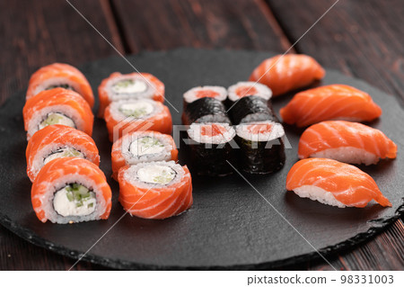 Sushi set from top on black background close-up. An assortment of various maki nigiri and rolls seafood soy sauce Sushi set from top on black background close-up. An assortment of various maki nigiri and rolls seafood soy sauce 98331003