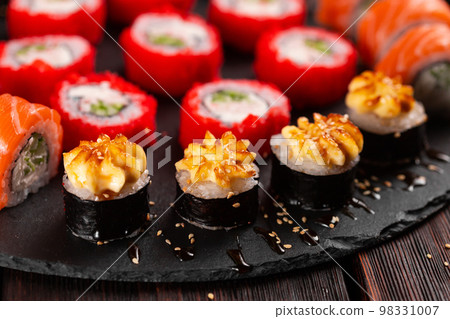 Large sushi set from top on black background close-up. An assortment of various maki nigiri and rolls seafood soy sauce Large sushi set from top on black background close-up. An assortment of various maki nigiri and rolls seafood soy sauce 98331007