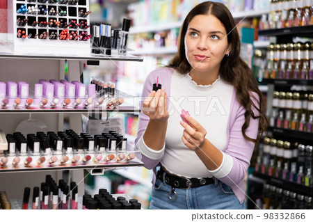 Female shopper choosing nail polish in cosmetics store 98332866