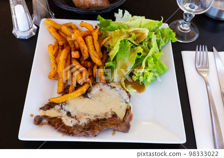 Beef steak with Roquefort sauce served with baked potatoes 98333022
