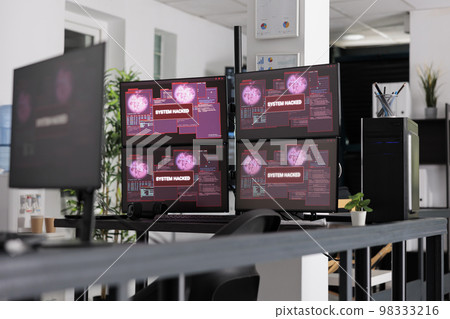 Software company having computers displaying critical error message showing on screen, dealing with hacking threat and pc malware. Empty desk with multiple monitors flashing security breach alert. 98333216