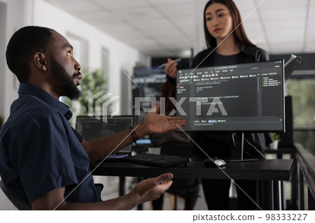 App developers working on temrinal window with html script and writing server code on computer, sitting in big data room. System engineer programming user interface in busy developing agency. 98333227
