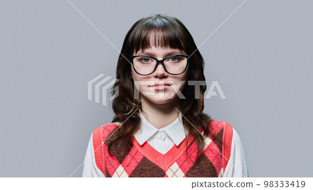 Portrait of young female student looking at camera on grey studio background Portrait of young female student looking at camera on grey studio background 98333419