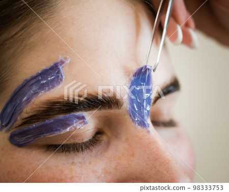 Eyebrow correction. The master removes excess hairs with wax and tweezers. 98333753