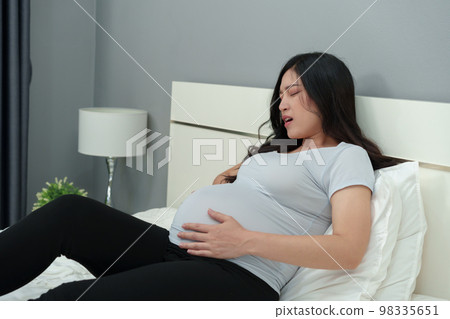 pregnant woman has a stomachache on bed 98335651