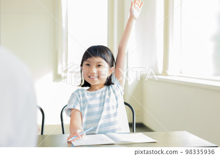 Child raising hand to answer in class 98335936