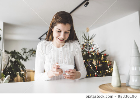 Smiling caucasian woman holding a baby monitor in her hands, looking at the screen Smiling caucasian woman holding a baby monitor in her hands, looking at the screen 98336190