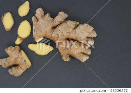Ginger rhizome with slices on black stone background Ginger rhizome with slices on black stone background 98336272