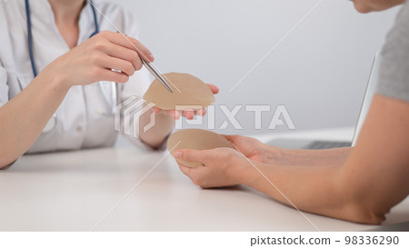 Caucasian woman and plastic surgeon choosing breast implants.  98336290