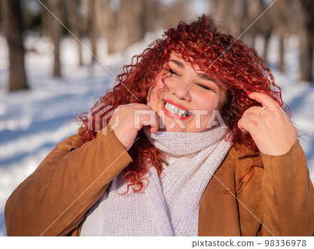 Portrait of a smiling chubby red-haired woman on a walk in winter. 98336978