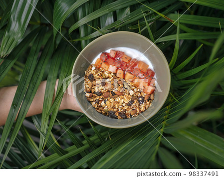 Bowl of fresh papaya muesli at the hand 98337491