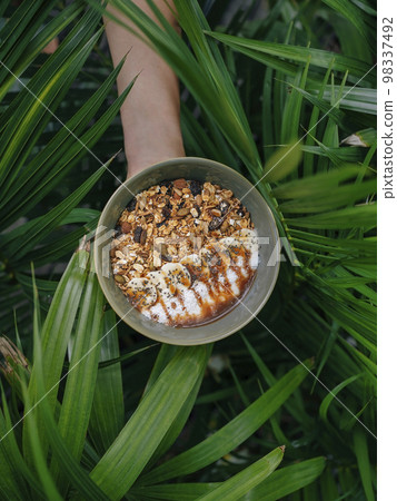 Bowl of fresh peanut butter muesli at the hand Bowl of fresh peanut butter muesli at the hand 98337492
