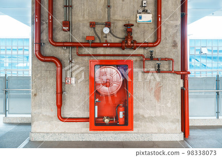 Fire extinguisher and water pump system on the wall, powerful emergency equipment for apartment and hotel 98338073