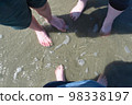 Feet in the beach sand covered with a small amount of water 98338197