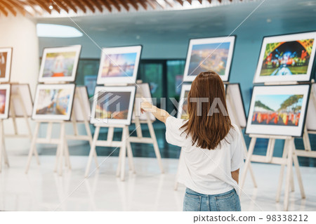 Young female tourist looking gallery exhibition. Art , photography and museum concept 98338212
