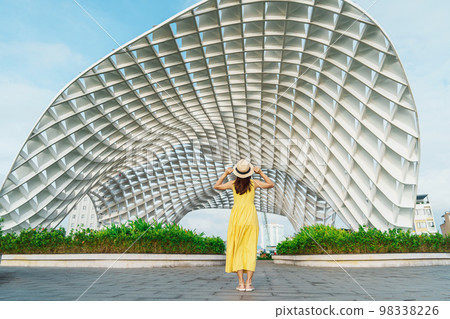 Woman Traveler with yellow dress visiting in Da Nang city. Tourist sightseeing the city building. Landmark and popular for tourist attraction. Vietnam and Southeast Asia travel concept 98338226