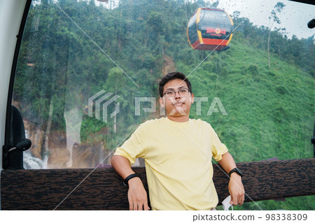 man sitting in Cable car with Ba Na Hills Mountain in the fog. Landmark and popular. Da Nang, Vietnam and Southeast Asia travel concept man sitting in Cable car with Ba Na Hills Mountain in the fog. Landmark and popular. Da Nang, Vietnam and Southeast Asia travel concept 98338309