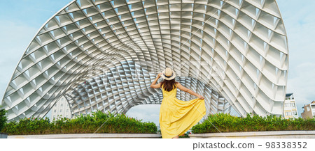 Woman Traveler with yellow dress visiting in Da Nang city. Tourist sightseeing the city building. Landmark and popular for tourist attraction. Vietnam and Southeast Asia travel concept Woman Traveler with yellow dress visiting in Da Nang city. Tourist sightseeing the city building. Landmark and popular for tourist attraction. Vietnam and Southeast Asia travel concept 98338352