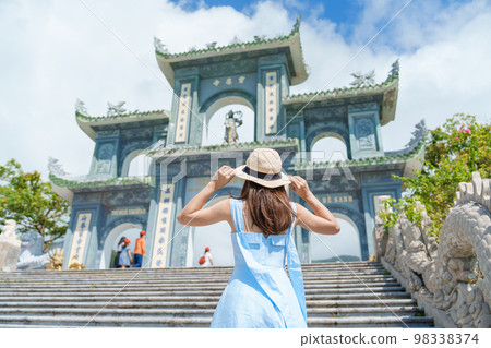 Woman traveler visiting at Linh Ung Pagoda temple, translation from Chinese character. Tourist with blue dress and hat traveling in Da Nang city. Vietnam and Southeast Asia travel concept 98338374