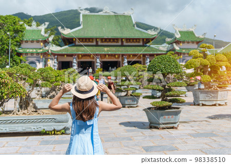 Woman traveler visiting at Linh Ung Pagoda temple or Lady big Buddha. Tourist with blue dress and hat traveling in Da Nang city. Vietnam and Southeast Asia travel concept 98338510