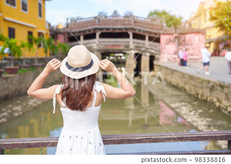 Woman traveler sightseeing at Japanese covered bridge or Cau temple in Hoi An ancient town, Vietnam. landmark and popular for tourist attractions. Vietnam and Southeast Asia travel concept 98338816