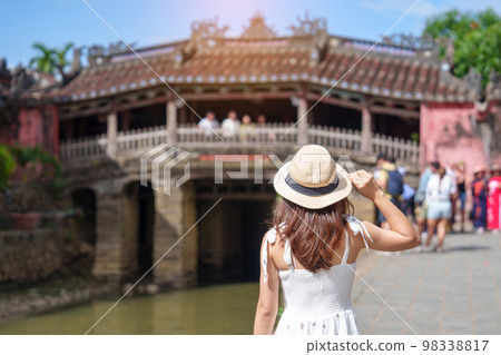 Woman traveler sightseeing at Japanese covered bridge or Cau temple in Hoi An ancient town, Vietnam. landmark and popular for tourist attractions. Vietnam and Southeast Asia travel concept 98338817