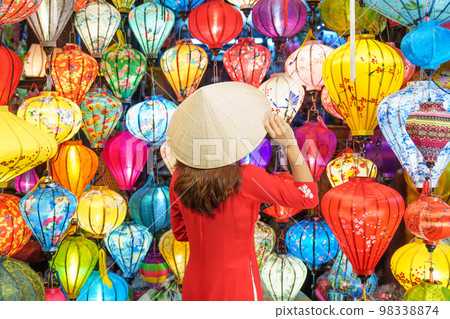 happy woman wearing Ao Dai Vietnamese dress with colorful lanterns, traveler sightseeing at Hoi An ancient town in central Vietnam.landmark for tourist attractions.Vietnam and Southeast travel concept 98338874