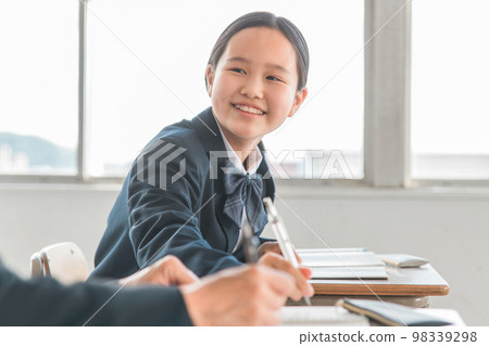 Junior high school student, high school student, elementary school girl (uniform) with a smile talking to friends during class in a school classroom 98339298