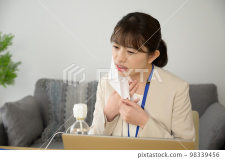 一位女士邊工作邊用加濕器潤濕喉嚨 98339456