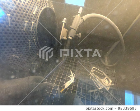 Shot blasting. Shot blasting of model printed on 3D printer from polyamide powder. A worker in sealed rubber gloves cleans the object by shot blasting in a shot blasting chamber. Industrial machine Shot blasting. Shot blasting of model printed on 3D printer from polyamide powder. A worker in sealed rubber gloves cleans the object by shot blasting in a shot blasting chamber. Industrial machine 98339693