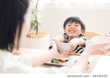 Family meal scene Boy refilling rice 98340204