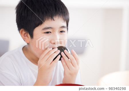 Family meal A boy eating a rice ball Family meal A boy eating a rice ball 98340298