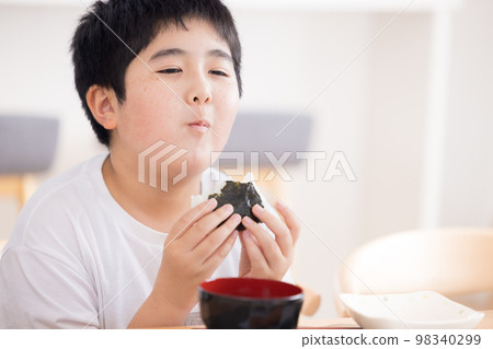 Family meal A boy eating a rice ball Family meal A boy eating a rice ball 98340299