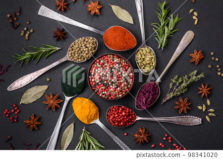 Variation of spices in metal spoons paprika, turmeric, cardamom, a mixture of allspice 98341020
