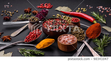 Variation of spices in metal spoons paprika, turmeric, cardamom, a mixture of allspice 98341047