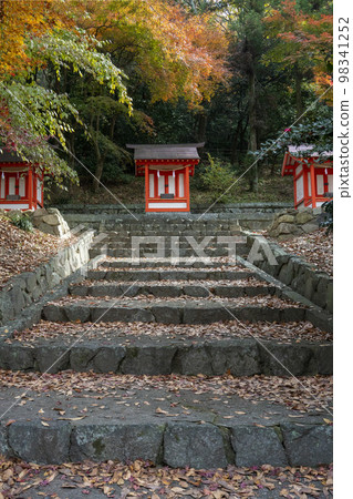 Kibitsu Shrine, Okayama City, three small vermillion-painted shrines on stone steps covered in fall foliage 98341252