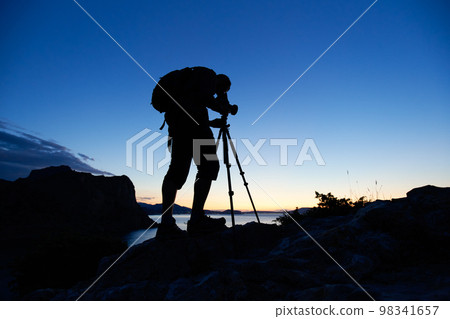 Silhouette of photographer on top of mountain Silhouette of photographer on top of mountain 98341657