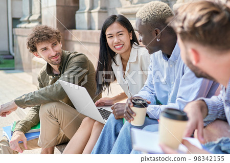 multicultural team of students is chatting on the steps of the campus. 98342155