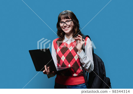 Smiling female student looking in camera on blue studio background 98344314