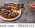 Woman hand holds shoulder blade with piece of plum tart or pie, selective focus 98345132