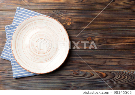 Top view on colored background empty round white plate on tablecloth for food. Empty dish on napkin with space for your design Top view on colored background empty round white plate on tablecloth for food. Empty dish on napkin with space for your design 98345505