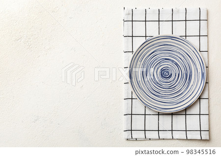 Top view on colored background empty round blue plate on tablecloth for food. Empty dish on napkin with space for your design Top view on colored background empty round blue plate on tablecloth for food. Empty dish on napkin with space for your design 98345516