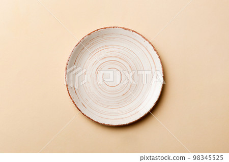 Top view of isolated of colored background empty round beige plate for food. Empty dish with space for your design 98345525