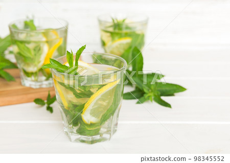Mojito cocktail. Refreshing mojito cocktail with lime, lemon and mint in a tall glass with a stick Mojito cocktail. Refreshing mojito cocktail with lime, lemon and mint in a tall glass with a stick 98345552