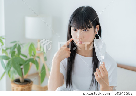 Z generation girl who wears a mask on her ear and cares about her skin condition 98345592
