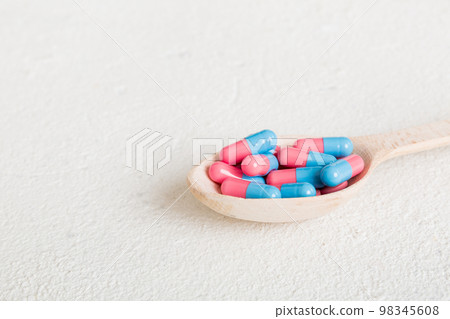 Vitamin capsules in a spoon on a colored background. Pills served as a healthy meal. Red soft gel vitamin supplement capsules on spoon Vitamin capsules in a spoon on a colored background. Pills served as a healthy meal. Red soft gel vitamin supplement capsules on spoon 98345608