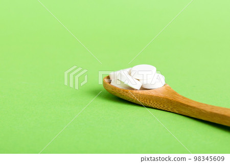 Heap of white pills on colored background. Tablets scattered on a table. Pile of red soft gelatin capsule. Vitamins and dietary supplements concept 98345609