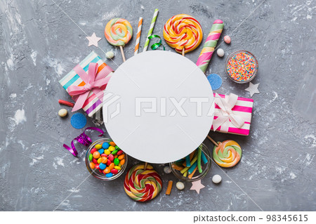 Flat lay holiday composition. Paper blank, lollipop, birthday decorations on Colored background. Top view, copy space for text 98345615