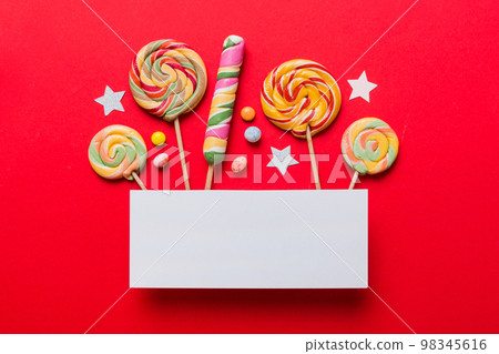 Flat lay holiday composition. Paper blank, lollipop, birthday decorations on Colored background. Top view, copy space for text 98345616